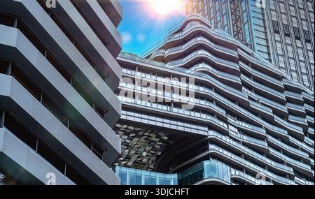 Modernes Stadtarchitektur-Konzept futuristisches Wolkenkratzergebäude Außenansicht mit flachem Blick auf die Sonne glänzende, geschwungene Linien Glasstruktur Luxusdesign ge Stockfoto