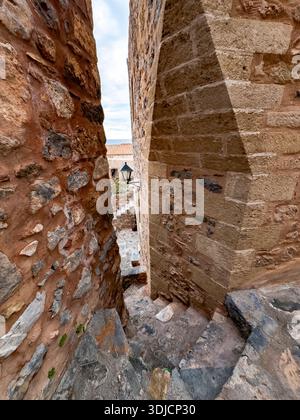 Gepflasterte Gasse mit traditionellen Häusern und Bougainvillea in der mittelalterlichen Stadt Monemvasia, Peloponnes, Griechenland. Stockfoto