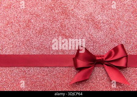 Rotes Satinband und Schleife schmücken einen glitzernden festlichen Hintergrund Stockfoto