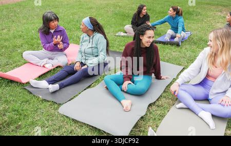 Multirassische Frauen, die Yoga-Übungen im Freien im Stadtpark machen - gesundes und sportliches Lifestyle-Konzept - Hauptfokus auf asiatisches Seniorengesicht Stockfoto