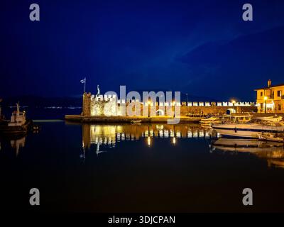Nächtlicher Blick auf den Hafen von Nafpaktos in Griechenland an Silvester mit beleuchteten venezianischen Festungsmauern, die sich im ruhigen Wasser spiegeln, vertäuten Booten und fe Stockfoto
