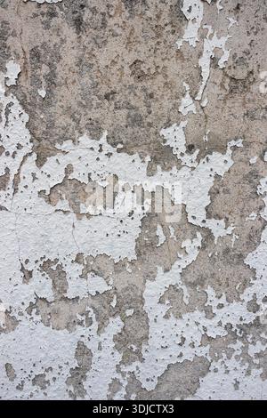 Stark verwitterte Wand mit abblätternder Farbe und freiliegendem Putz, der einen gruseligen, verstörten Texturhintergrund schafft Stockfoto