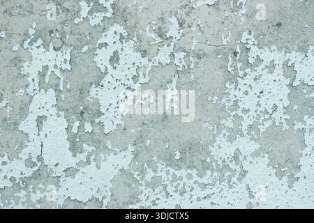 Stark verwitterte Wand mit abblätternder Farbe und freiliegendem Putz, der einen gruseligen, verstörten Texturhintergrund schafft Stockfoto