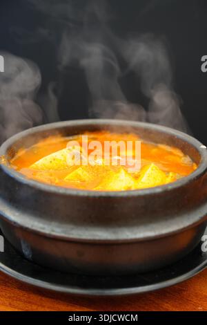 Dampfender heißer koreanischer, scharfer Tofu-Eintopf (Sundubu-jjigae), serviert in einem traditionellen Töpfertopf (Ttukbaegi) Stockfoto
