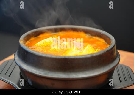 Dampfender heißer koreanischer, scharfer Tofu-Eintopf (Sundubu-jjigae), serviert in einem traditionellen Töpfertopf (Ttukbaegi) Stockfoto