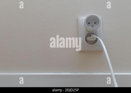 Stecker an eine Steckdose, eine intelligente Steckdose, eine Steckdose an einer weißen Wand in einem Raum Stockfoto
