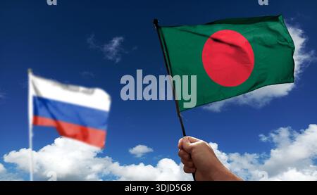 Bangladesch-Flagge winkt unter Wolken. Fliegen Sie in den Himmel. Foto der russischen Flagge mit absichtlich verschwommenem Hintergrund Stockfoto