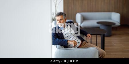 Hochwinkelansicht eines männlichen Anwalts, der auf dem Sofa sitzt und wegschaut und über Rechtsstrategien nachdenkt Stockfoto