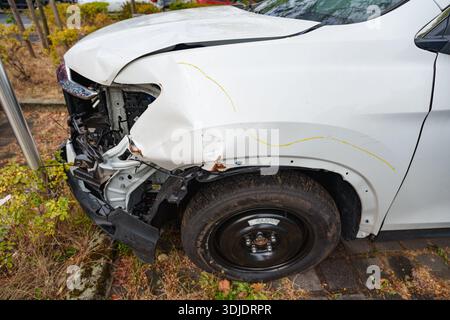 Beschädigter weißer Pickup mit eingeklemmtem vorderen Stoßfänger und Reserverad nach dem Aufprall Stockfoto