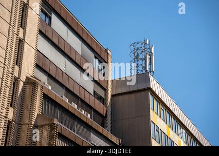 Ljubljana, Slowenien - 10. August 2025: Ein schräg nach oben gerichteter Blick auf ein Bürogebäude im brutalistischen Stil in Ljubljana mit strukturiertem Ziegelwerk und Metallshu Stockfoto