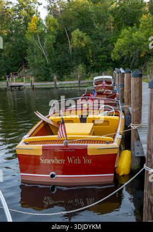 NISSWA, MN - 12. SEP 2024: Klassisches Vintage-Motorboot aus Holz, das auf dem Wasser schwimmt, mit einem Seil an die Anlegestelle an einem Minnesota-See gebunden. Stockfoto