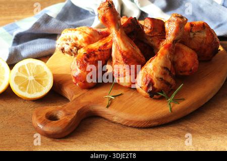 Gegrilltes Huhn, scharfe gegrillte Hähnchenschenkel, Drumsticks mit Paprika, Zitrone und frischen Kräutern auf dem Schneidebrett. Grillgerichte Stockfoto