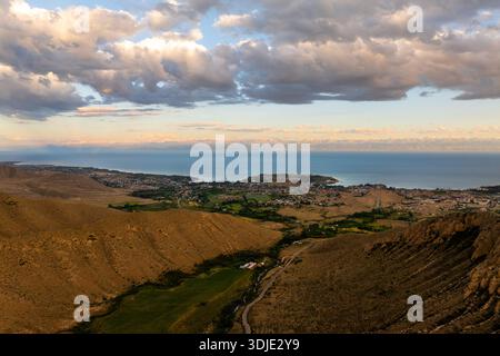 Der Blick aus der Luft fängt atemberaubende Berge und einen sich windenden Fluss durch ein üppiges Tal bei Sonnenuntergang ein. Die malerische Landschaft bietet lebendige Farben und natürliche Schönheit. Stockfoto