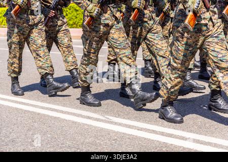 Das Militär marschiert tagsüber in disziplinierter Formation auf einer asphaltierten Straße. Stockfoto