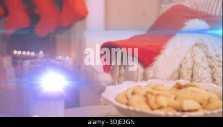 Mit weißer Muschelschale mit Keksen auf der Vorderseite des Tisches, Kerzenfleck und Weihnachtsmann-Hut Stockfoto