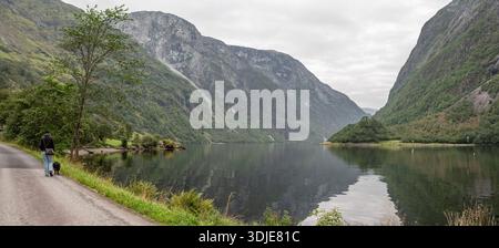 Eine Frau mit ihrem Hund wandert durch Naeroyfjord, Norwegen Stockfoto