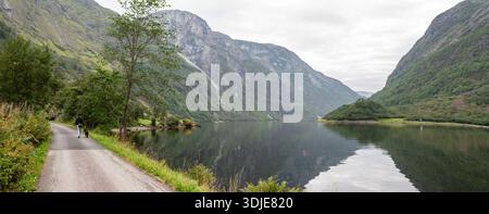 Eine Frau mit ihrem Hund wandert durch Naeroyfjord, Norwegen Stockfoto