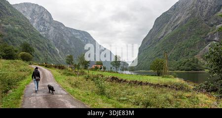 Eine Frau mit ihrem Hund wandert durch Naeroyfjord, Norwegen Stockfoto