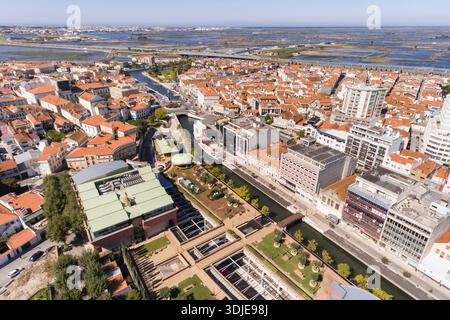 Blick aus der Vogelperspektive auf die pulsierenden Terrakotta-Dächer, die sich hinabstürzen und auf die ruhigen Kanäle treffen, die sich durch das Herz der Stadt, Aveiro, Portugal, schlängeln. Stockfoto