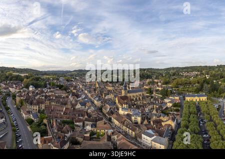 Blick aus der Vogelperspektive auf die Altstadt, die ockerfarbene Dächer mit dem goldenen Glanz der alten Steinbauten verbindet, eingebettet zwischen lebhaften grünen Bäumen, Sarlat, Dordogne, F Stockfoto