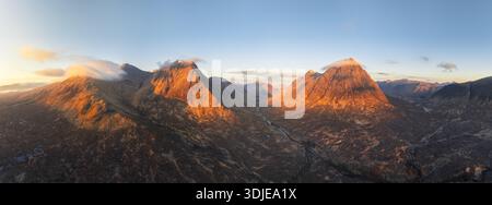 Aus der Vogelperspektive des goldenen Sonnenlichts, das die dramatischen Gipfel der Glencoe Mountains küsst und lange Schatten über den zerklüfteten Talboden wirft, Ballachulish, SCO Stockfoto