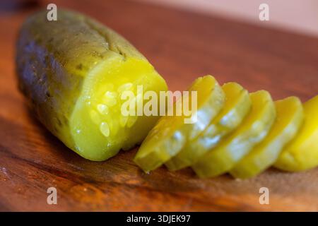 Makroaufnahme einer frischen grünen Dill-Gurke, teilweise in Runden geschnitten. Das Bild betont das feuchte, schäbige Innere der Scheiben und die Charakteristika Stockfoto