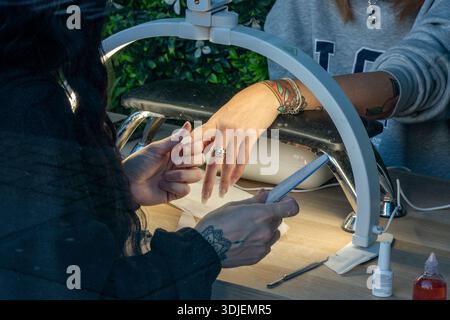 Nahaufnahme einer Frau, die in einem Nagelbalken oder Salon behandelt wird, Nagelbehandlung und Maniküre mit Techniker und Kunde in Nagelbalken-Nahaufnahme Stockfoto