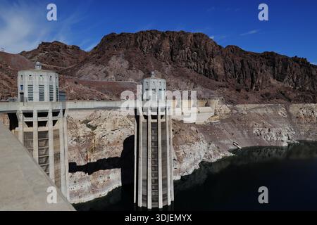 Beton-Ansaugtürme und Staudamm am Hoover Dam an der Grenze zu Nevada Arizona in den USA ragen über dem Stausee und felsigen Hängen unter blauem Himmel. Stockfoto