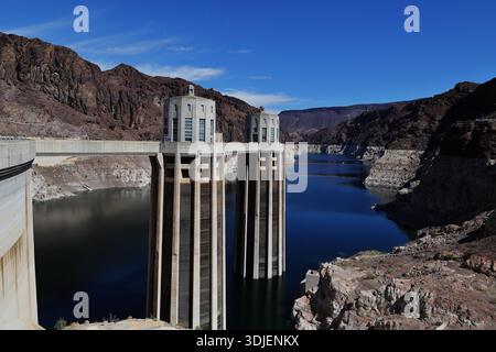 Zwei Beton-Einlasstürme am Hoover Dam an der Grenze zu Nevada Arizona in den USA erheben sich über einem blauen Reservoir-Kanal zwischen felsigen Hängen mit Wolken. Stockfoto