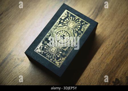 Wahrsager- und Whitcraft-Konzept mit Tarotkarten auf rotem Samt, umgeben von einer magischen Kristallkugel, einem goldenen Armband, einem Buch und einer Holzbox Stockfoto