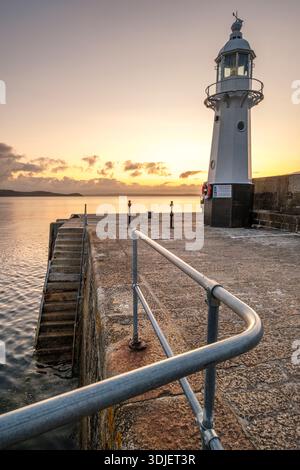 Sonnenaufgang über dem Leuchtturm an der Hafenmauer von Mevagissey, Cornwall Stockfoto
