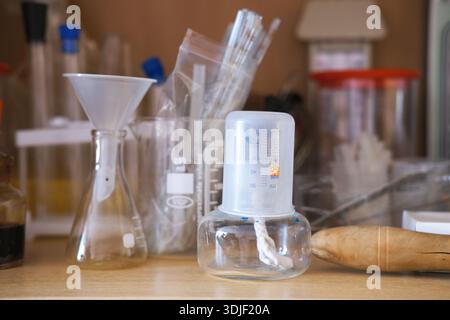 Sammlung von Laborglaswaren auf Holzregalen ausgestellt, mit verschiedenen Kolben, Bechern und Messgeräten, die wissenschaftliche Entdeckungen veranschaulichen Stockfoto