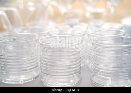 Klare Glasbecher mit gerippter Textur sind eng auf einer Oberfläche angeordnet und zeigen Reflexionen und Highlights in einer hellen Umgebung mit weichem Hintergrund Stockfoto