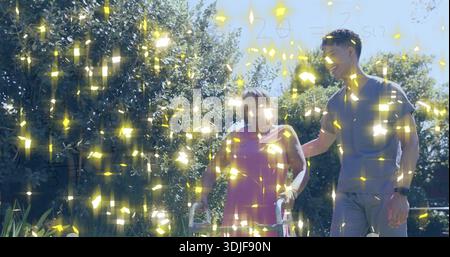 Eine ältere Frau, die Walker auf dem Gartenweg benutzt, rosafarbenes Kleid, Mann mit Uhr, goldenes Licht Stockfoto