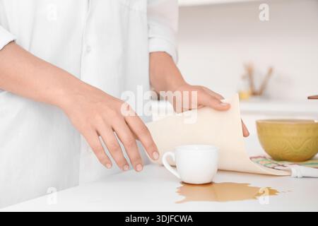 Frau, die verschütteten Kaffee auf der Theke in der Küche abwischt, Nahaufnahme Stockfoto
