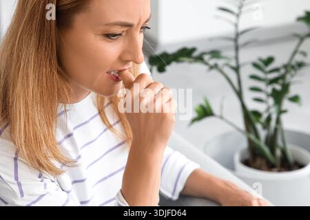 Besorgte reife Frau beißt zu Hause Nägel Stockfoto