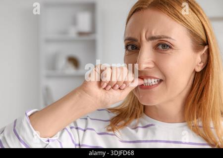 Besorgte reife Frau beißt zu Hause Nägel Stockfoto