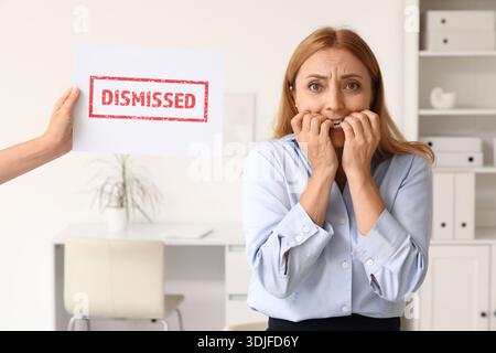 Besorgte, reife Geschäftsfrau beißt Nägel und hält Papier mit Wort im Amt Stockfoto