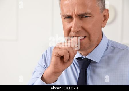 Besorgter reifer Geschäftsmann beißt Nägel im Büro Stockfoto