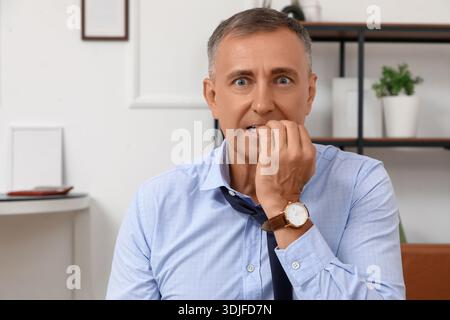 Besorgter reifer Geschäftsmann beißt Nägel im Büro Stockfoto