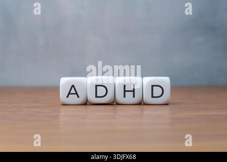 Vier weiße Würfel, die ADHS auf einem Holztisch beschreiben. Medizin- und Gesundheitskonzept. Stockfoto