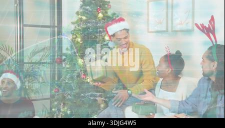 Lächelnder Mann in Senfpullover, der Weihnachtsmütze trägt, der ein Geschenk zu Hause in der Nähe des dekorierten Weihnachtsbaums hält Stockfoto