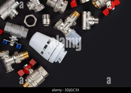 Wasserkugelventil mit Anschlussstück und Thermostatventilkopf auf Rindenhintergrund. Stockfoto