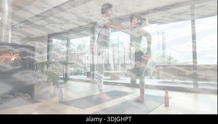 Zwei Frauen in Leggings üben, die im Wohnzimmer eine Gleichgewichtsstellung halten, mit Yogamatten Stockfoto
