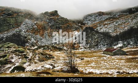 Eine dramatische Berglandschaft mit traditionellen Steinhütten (Capanne di Lago Scuro) in einem felsigen Tal. Stockfoto
