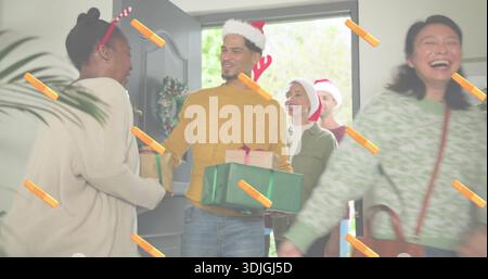 Begrüßung eines Mannes in senfgelbem Pullover, der Geschenkverpackungen vor der Tür, Kranz und Hüte überreicht Stockfoto