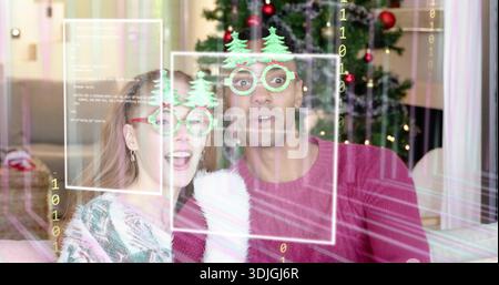 Paare, die im Wohnzimmer sitzen und eine baumförmige Brille tragen, stricken, die Weihnachtsbaum überlagern Stockfoto