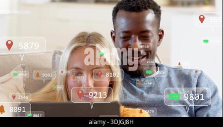 Sitzungspaar Betrachten Laptop im Wohnzimmer Mann blau Pullover Frau helle Oberseite digitale Overlays Stockfoto