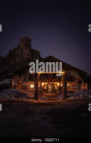 Wintersonnenuntergang am Passo Giau in den Dolomiten, wo warme alpine Lichter mit schneebedeckten Gipfeln unter einem dramatischen violetten Himmel kontrastieren. Stockfoto