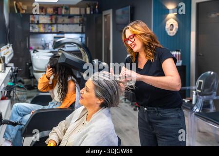 Friseur, der im Salon am Haar des Kunden arbeitet Stockfoto